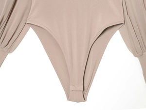 Dettaglio del body beige con bottoni automatici sul cavallo e maniche a lanterna