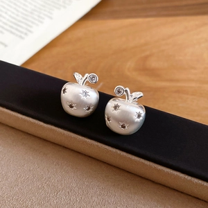 Macro view of matte silver apple earrings featuring sparkling zircon and brushed texture