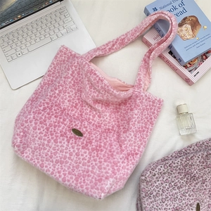 Gros plan d'un sac cabas en peluche imprimé léopard rose avec plaque de marque en métal