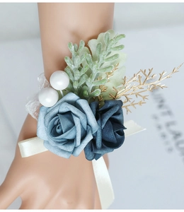 Detail of blue artificial rose wrist corsage with golden leaves and pearl accents