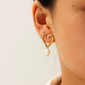 Boucles d'oreilles cœur martelé doré avec perles portées par un mannequin