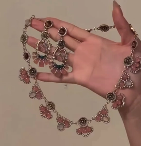 Detail of vintage necklace and earrings set with pink flower charms and crystal accents