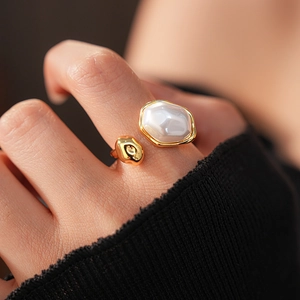 Gros plan d'une bague ajustable dorée avec une grande perle ovale blanche et insert métal