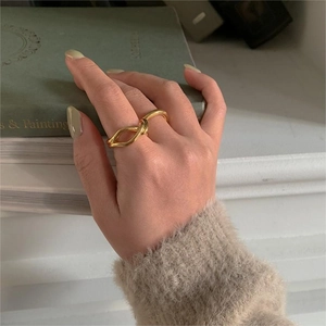 Close-up of a minimalist golden knot ring worn on finger against vintage book background