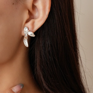 Detail view of silver floral earrings with organic metal texture on female model