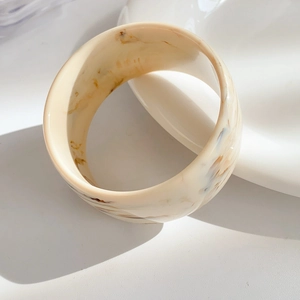 Detailed close-up of cream marble resin bangle with elegant brown swirl patterns