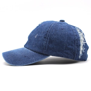 Dettaglio del berretto da baseball in denim blu navy con fori consumati e trama vintage
