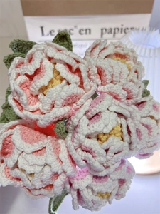Detailed macro of handmade crochet peony bouquet with pink petals and green leaves