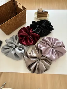 Detail of five oversized satin scrunchies in various colors with elegant silk texture