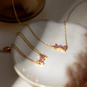 Elegant 18k gold stainless steel necklace featuring a pink gemstone bow pendant