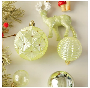 Detailed view of pale yellow textured Christmas baubles and a glittery green deer ornament
