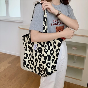 Detailed shoulder view of a leopard print canvas tote bag shown in use by a model
