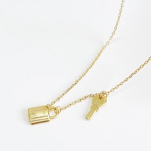 Minimalist 925 sterling silver gold necklace with lock and key pendants on white background