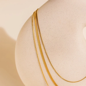 Close-up of three-layered 18K gold plated snake bone chain and metal necklaces