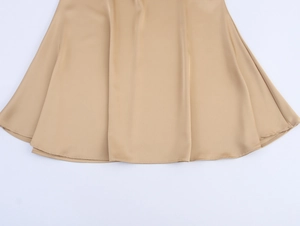 Detailed view of champagne satin maxi skirt hem featuring smooth draping and fine stitching