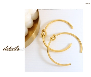 Macro shot of polished gold-plated knot detail on a minimalist open-cuff bracelet