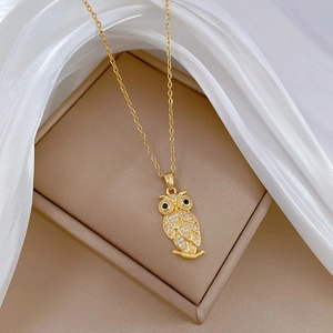 Luxurious gold owl pendant necklace with sparkling crystals on a soft beige display