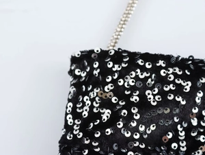 Detailed macro view of sequin embellishments and silver bead chain on black fabric
