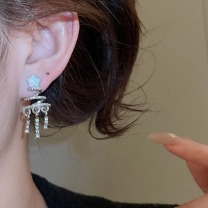 Detail of silver Christmas tree tassel earrings with sparkling rhinestones worn by a model