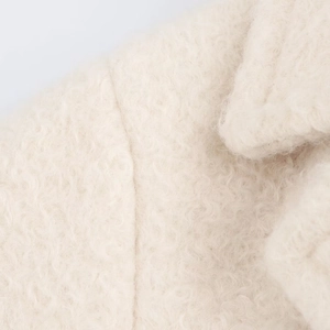 Detailed macro view of the cream curly faux shearling fabric and stitching on the coat
