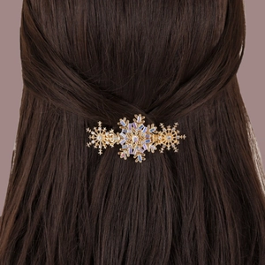 Elegant gold snowflake hair clip with rhinestones worn on a woman's brown hair