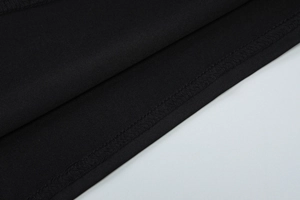Detail view of double-needle hem stitching on a black high-neck sleeveless dress