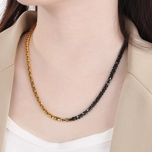 Détail d'un collier bicolore en acier inoxydable or et noir porté par un mannequin