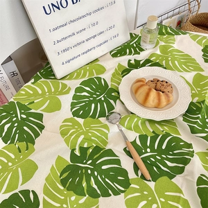 Close-up of Monstera leaf pattern on Nordic style cotton linen tablecloth with dining setup