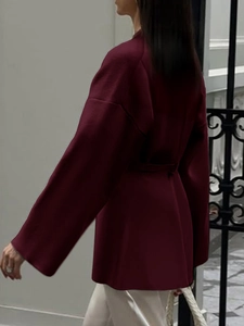 Detail of elegant dark red long-sleeve belted coat with a smooth flowing silhouette
