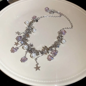 Détail du collier à pampilles argenté avec papillon violet, perles et étoiles
