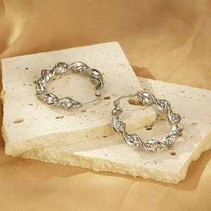 Silver twisted hoop earrings with diamonds on stone and gold satin background