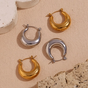 Detailed view of thick U-shaped hollow hoop earrings in polished gold and silver finishes
