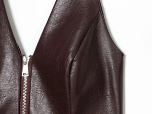 Detalle de top halter de cuero sintético granulado con una cremallera frontal plateada