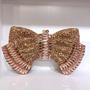 Detail of champagne gold bow-shaped clutch bag with luxury rhinestones and metal clasps