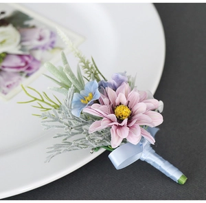 Macro detail of artificial daisy boutonniere with pink petals and blue ribbon stem