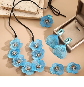 Dettaglio del set di gioielli floreali blu con collana, orecchini e anello su pietra