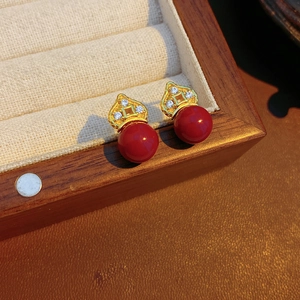 Close-up of retro red floral stud earrings with gold plating and sparkling crystal accents