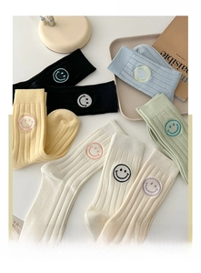 Detail of colorful cotton crew socks featuring embroidered smiley face icons and ribbed texture