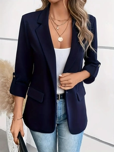 Detail of dark blue blazer lapel with decorative pockets and gold coin necklace
