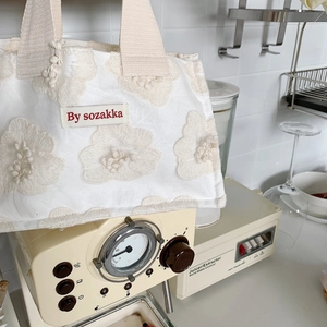 Detail of 3D floral embroidery on white canvas lunch bag with beige woven handle