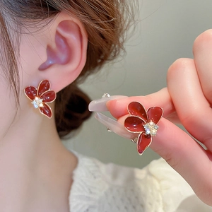 Détail d'une boucle d'oreille fleur rouge avec pétales en émail et centre en cristal