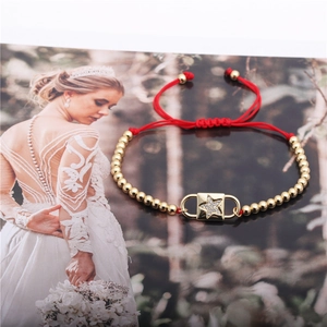 Detail eines verstellbaren roten Kordelarmbands mit Goldperlen und Stern-Zirkonia-Anhänger