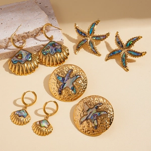 Golden stainless steel seashell and starfish earring set on beige stone background