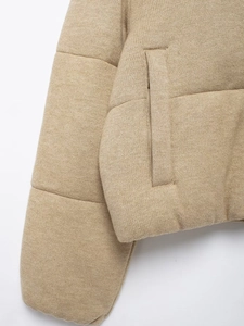 Detailed close-up of beige knitted jacket showing textured fabric and side pocket design