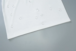 Dettaglio dell'abito bianco a coste con eleganti strass a goccia applicati sul tessuto