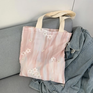 Détail de la broderie florale sur un sac cabas en toile posé sur un canapé en tissu