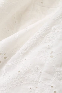 Close-up of white broderie anglaise embroidery fabric on the cotton blazer set