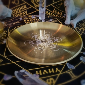 Close-up of golden metal altar plate featuring an intricate Flower of Life geometric pattern