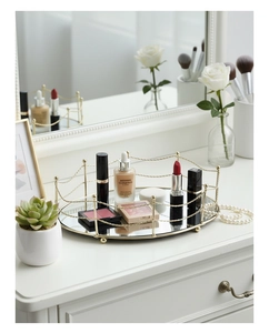Detail of elegant gold mirrored tray featuring wavy metal railings and glass surface