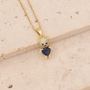 Detailed close-up of a gold bear pendant with a blue heart-shaped stone and zircon inlay